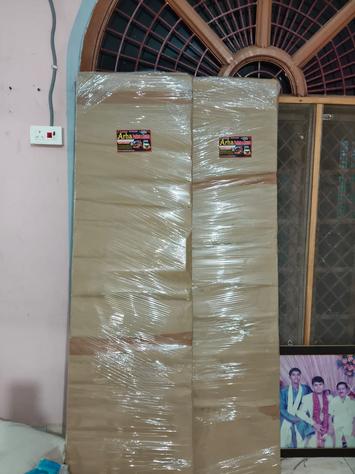 Two large wrapped furniture pieces placed near a window